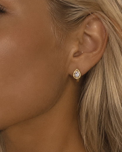 Pear lab-grown diamond framed huggie earring in 14k solid gold, worn on the ear