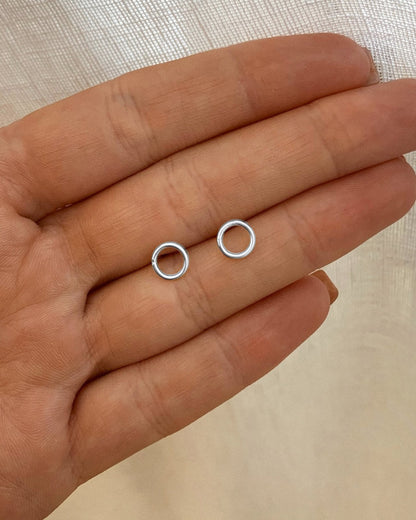 Circle Stud Earrings in Sterling Silver, held in a palm - Hypoallergenic | The Littl